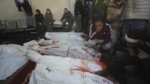 Un grupo de gazatíes velan a familiares muertos en el bombardeo israelí de este lunes, en la morgue del hospital de Rafah.