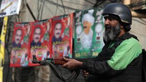 Un agente de seguridad vigila la distribución de propaganda electoral días antes de las elecciones en Pakistán.