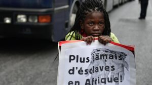 Una niña sujeta una pancarta con el lema &quot;Nunca más en esclavos en África&quot; en una protesta de migrantes en Grecia.