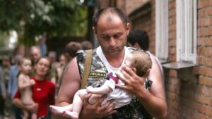 A Russian police officer carries a released baby from a school seized by heavily armed masked men and women in the town of Beslan in the province of North Ossetia near Chechnya, in this September 2, 2004 file photo.