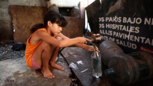 Una niña rellena una botella de agua para llevar a casa en Villa Fiorito, un vecindario de clase obrera a las afueras de Buenos Aires, el pasado 27 de febrero.