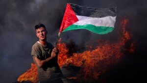 Un joven ondea la bandera de Palestina junto a la valla fronteriza al este de la ciudad de Gaza.
