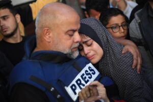 El periodista palestino de Al Jazeera, Wael Dahdouh, abraza a un familiar mientras lamenta la muerte de su hijo.