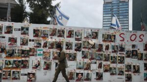 Una soldado pasa junto a un mural con los rostros y los nombres de los secuestrados por Hamás, en la llamada Plaza de los Rehenes de Tel Aviv
