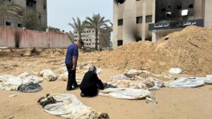 Una mujer junto a un grupo de cadáveres de palestinos desenterrados de una fosa común junto al hospital Nasser de Jan Yunis.