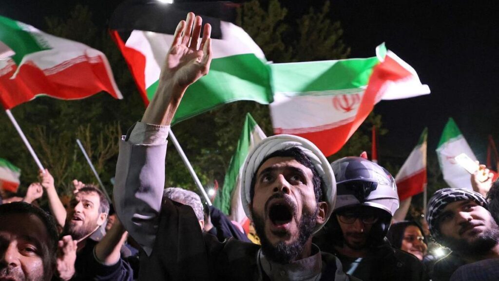 Varios manifestantes ondean banderas de Palestina e Irán frente a la embajada del Reino Unido en Teherán, momentos después de los ataques a Israel.