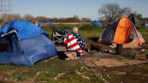 Una persona 'homeless' envuelta en una bandera de EEUU en un campamento en Sacramento, California