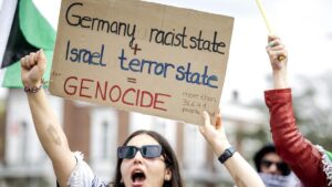 Una mujer muestra un cartel contra Israel y Alemania en una protesta frente al Tribunal Internacional de Justicia, este lunes en La Haya.
