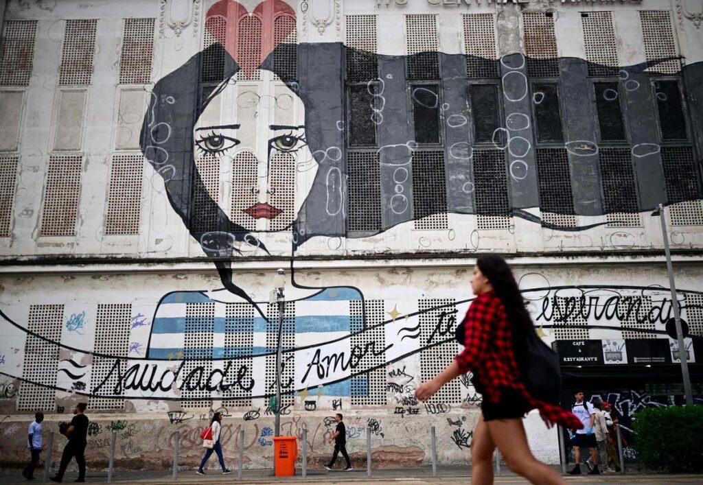 Una mujer camina delante de un murual en el bulevard donde se celegra la cumbre social del G20, en Rio de Janeiro.