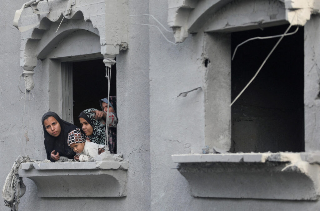 Palestinos miran desde una ventana el lugar de un ataque israelí contra una casa, en medio del conflicto entre Israel y Hamás, en el campo de refugiados de Nuseirat, en el centro de la Franja de Gaza, 7 de diciembre de 2024.