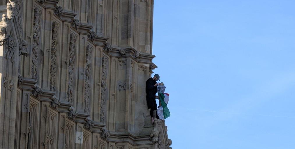 Un hombre se encarama a la torre del Big Ben enarbolando la bandera palestina