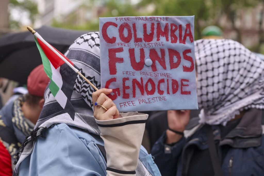 Un recién graduado de Columbia utiliza una gorra de graduación como pancarta de protesta, mientras estudiantes, ex alumnos y profesores protestan contra las inversiones de la universidad en Israel, en la Universidad de Columbia