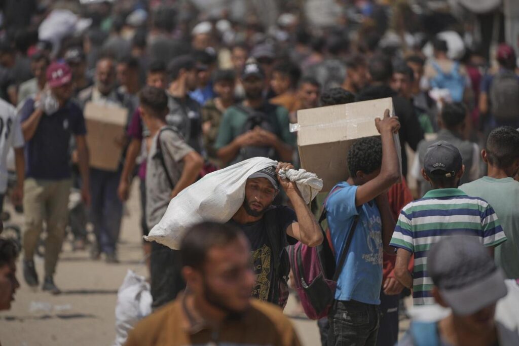 Palestinos cargan cajas y bolsas con comida y ayuda humanitaria distribuidas por la Fundación Humanitaria de Gaza.