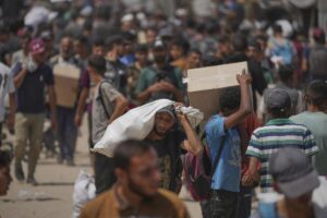 Palestinos cargan cajas y bolsas con comida y ayuda humanitaria distribuidas por la Fundación Humanitaria de Gaza.