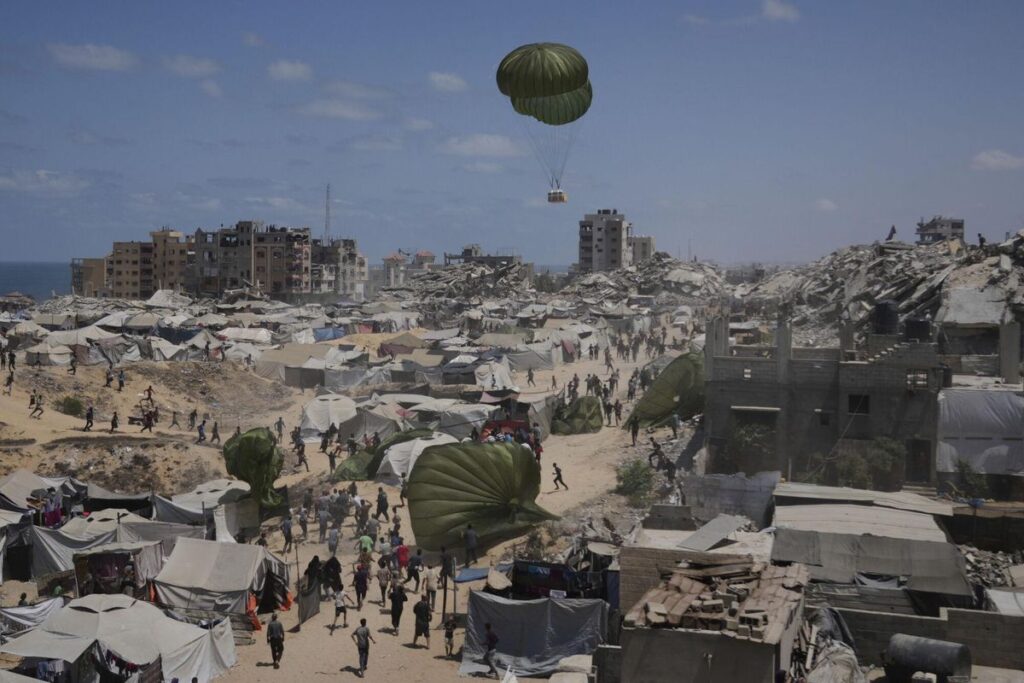 Palestinians rush to collect humanitarian aid airdropped by parachutes into Gaza City, northern Gaza Strip, Aug. 7, 2025. (AP Photo/Jehad Alshrafi) Associated Press/LaPresse. EDITORIAL USE ONLY/ONLY ITALY AND SPAIN