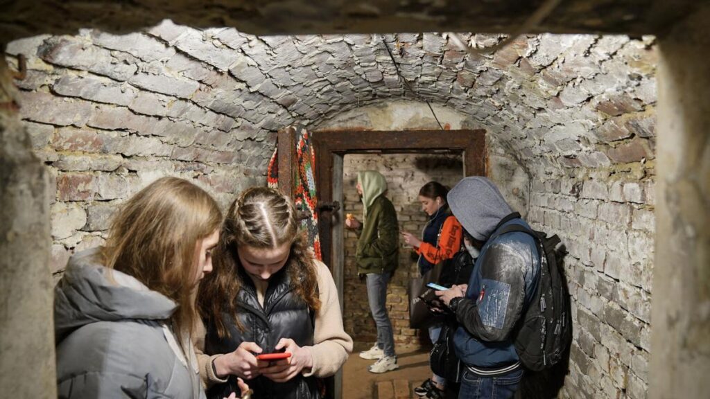 Ciudadanos de Lemberg, en Ucrania, consultan sus teléfonos móviles en un refugio durante un bombardeo ruso.