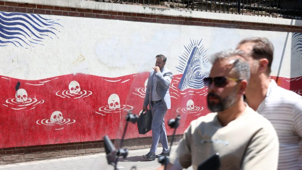 Ciudadanos iraníes pasan frente a un mural contra Estados Unidos en Teherán.
