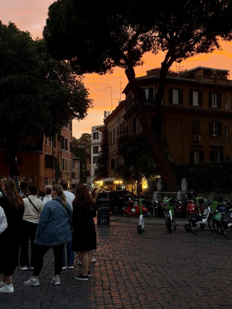 Atardecer en el barrio del Trastevere de Roma, con patinetes y bicicletas de alquiler sobre una acera.