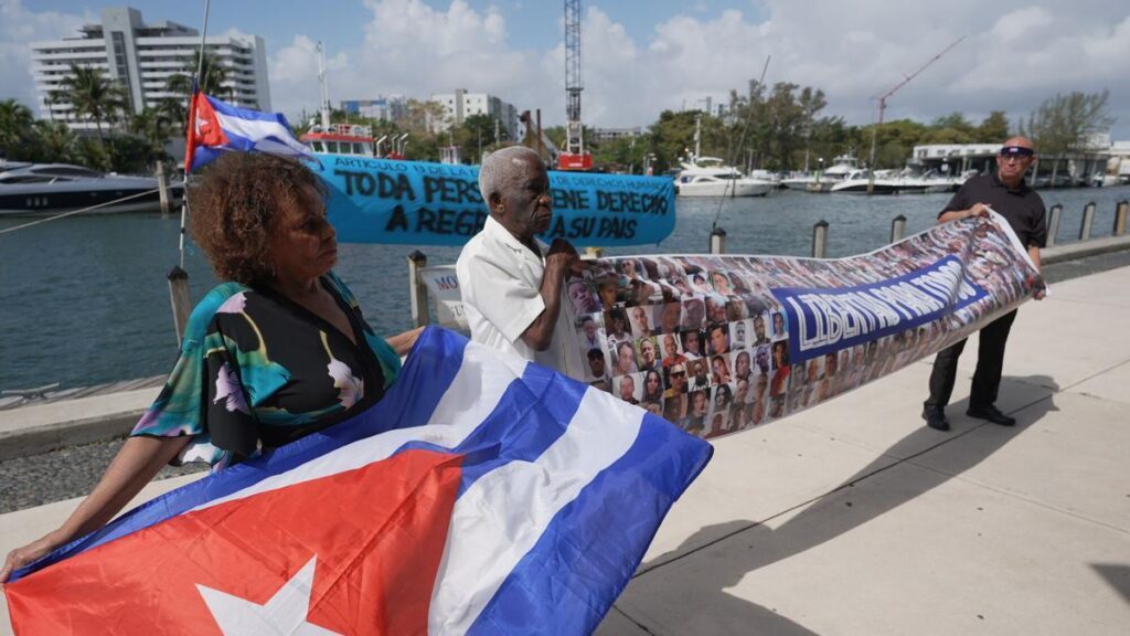 Olga Gómez y Félix Cifuentes, de la organización cubana Alfa 66, junto a Osvaldo Hernández, de Vigilia Mambisa ,sostienen una bandera de Cuba este lunes, en el Parque Lummus en Miami (Estados Unidos). Piden al presidente de Estados Unidos, Donald Trump, que permita enviar ayuda. EFE/ Alberto Boal. CONCENTRACION