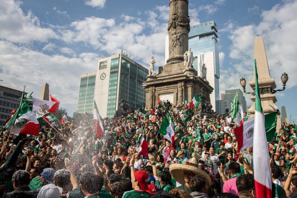 Aficionados celebran el triunfo de México en el Ángel de la independencia.