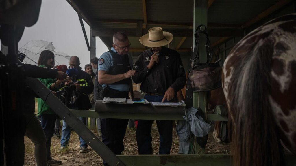 El gerente de un centro ecuestre conversa con un agente de policía mientras se preparan para continuar la búsqueda con la ayuda de caballos de Lyhanna, de 11 años, quien desapareció el 29 de mayo tras subir al coche de un hombre frente a su escuela secundaria en la localidad de Fleurance, al oeste de Toulouse, el 4 de junio de 2026.