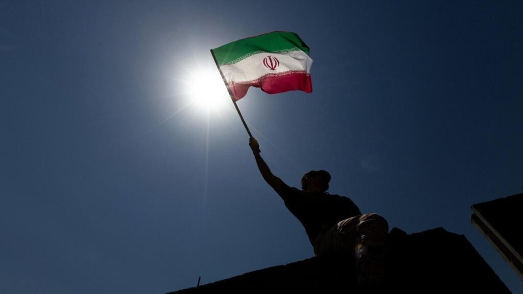 Un hombre ondea la bandera de Irán.
